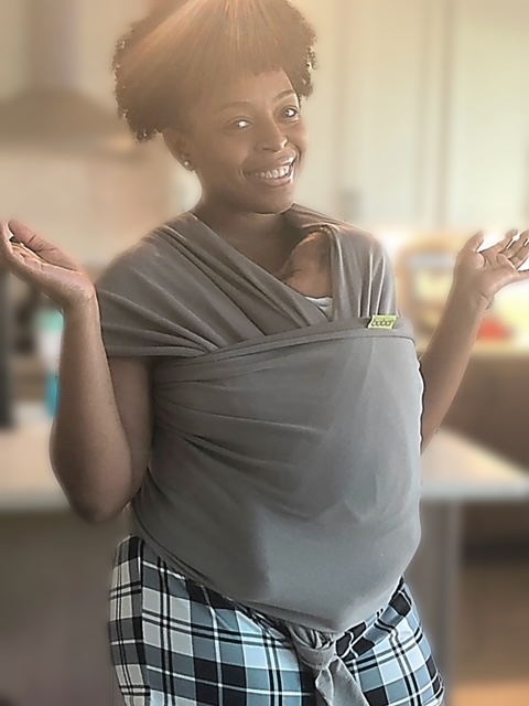 African American woman carrying a baby in a Boba Wrap Carrier. Her hands are up showing that she is hands free when wearing the child in the carrier.